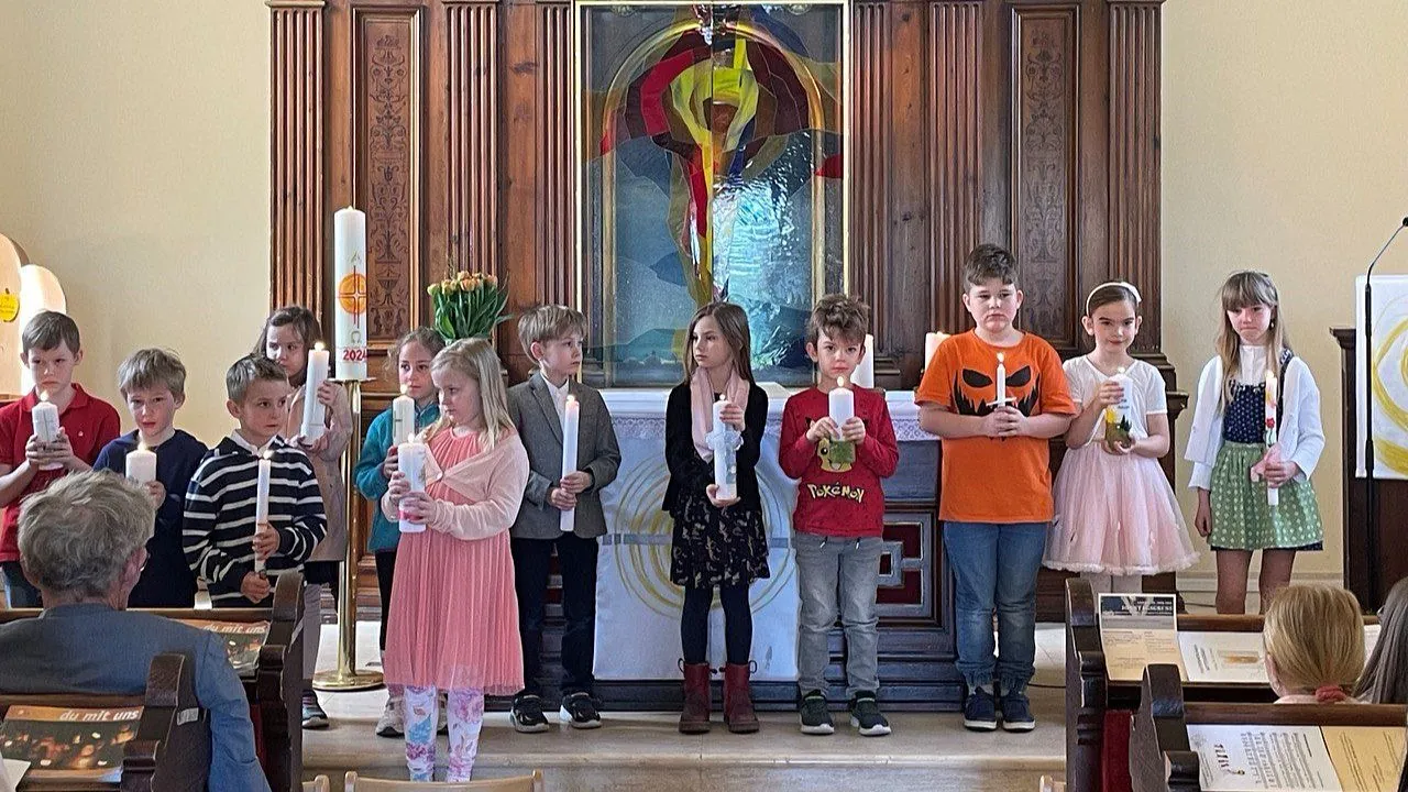 Kinder mit Kerzen stehen vor einem Altar